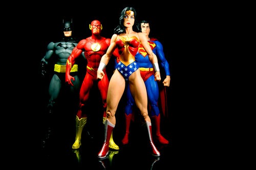 Vancouver, Canada - October 9, 2012: Action figure models of Wonder Woman, The Flash, Superman and Batman, released by DC comics, against a black background.